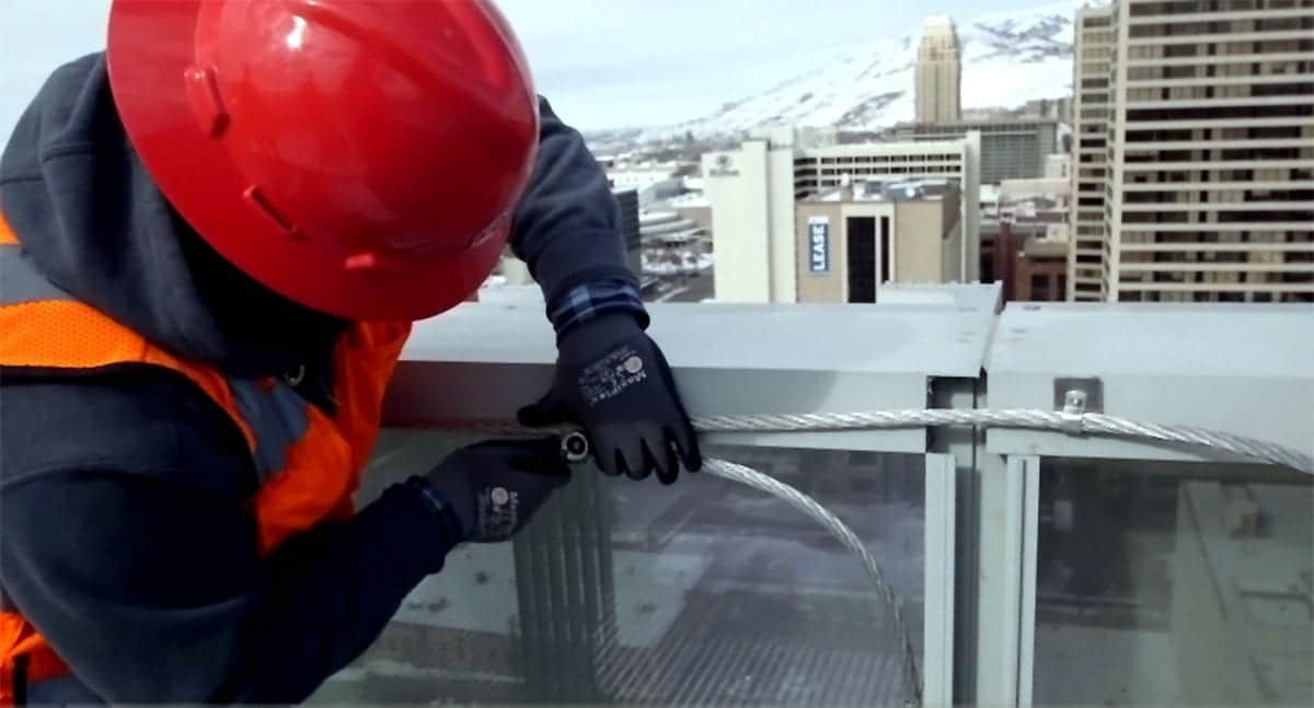 雷保護の実装に使用されるワイヤーを締めている建設作業員の写真。