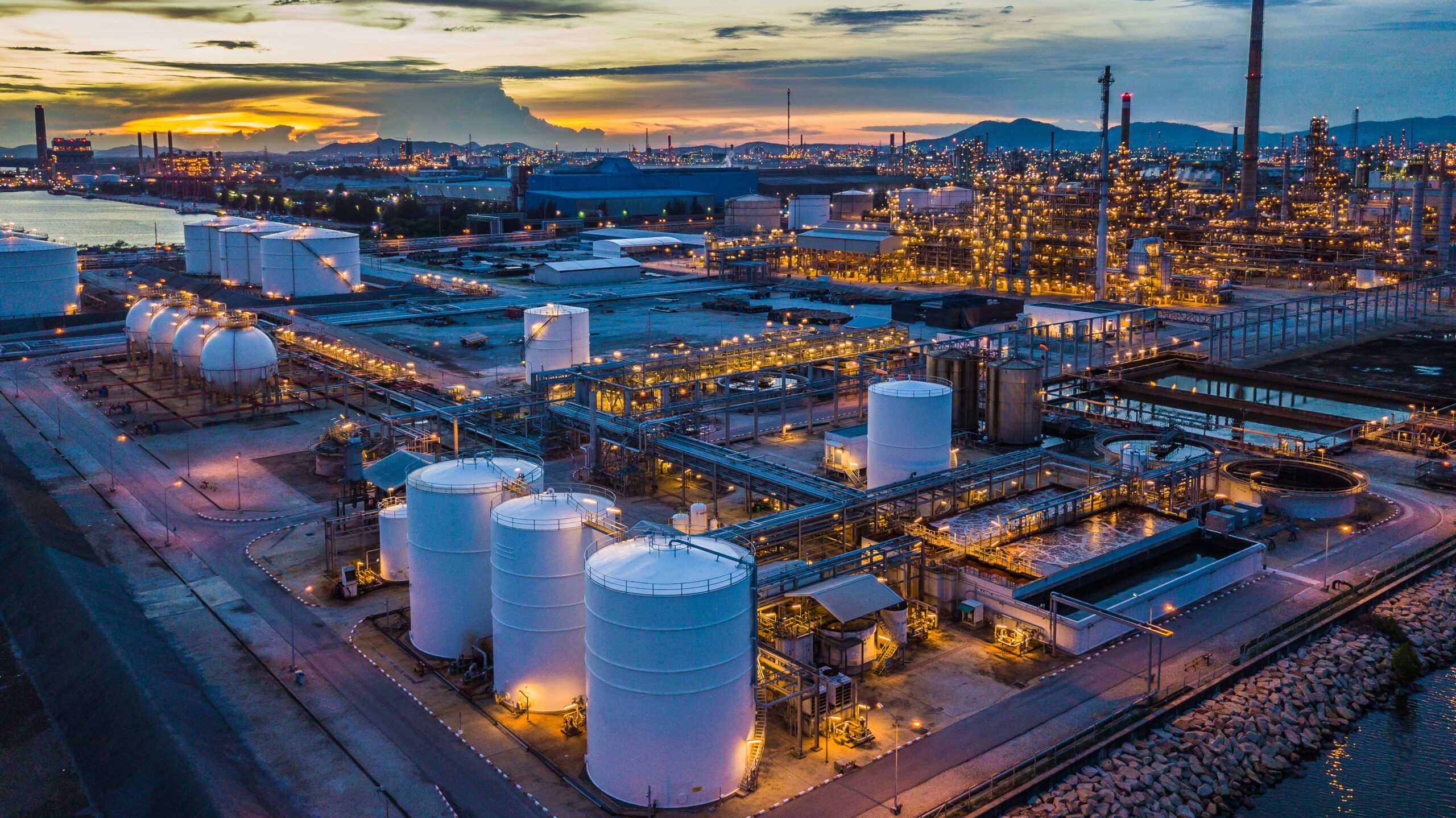 Aerial view oil terminal is industrial facility at night for storage of oil and petrochemical products ready for transport to further storage facilities in city skyline.